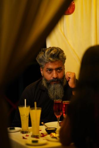 a man with a beard sitting at a table at Mount Stratus Resort Vayalada in Bālūssheri