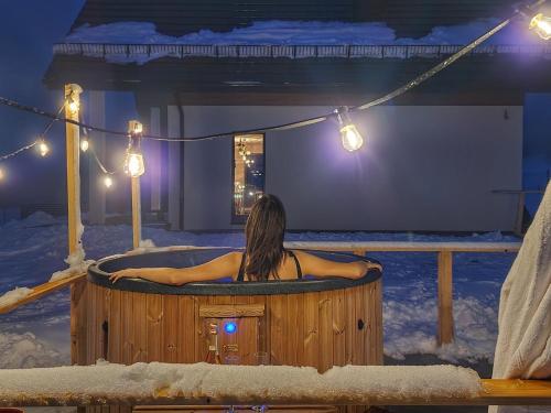 uma mulher sentada numa banheira de hidromassagem na neve em Lackowa Chill and Rest dom z balią em Uście Gorlickie