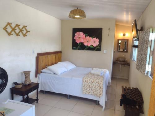 ein Schlafzimmer mit einem Bett und einem Gemälde von rosa Blumen in der Unterkunft Pousada Cantinho do Dodó in Mulungu
