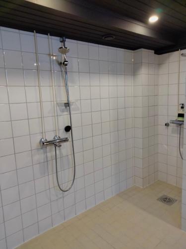 a shower in a bathroom with white tiles at Kuhmoisten Kivilinna in Kuhmoinen