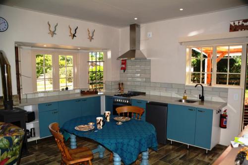 una cocina con armarios azules y una mesa y sillas azules en The Corner House Sa en Howick