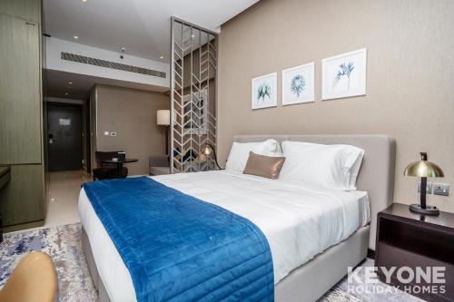 a bedroom with a large bed with a blue blanket at KeyOne - Studio in DAMAC Maison Privé in Dubai