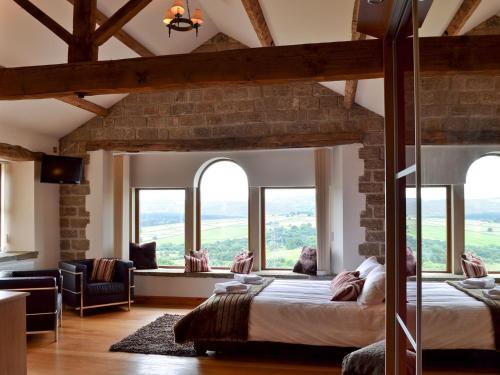 a bedroom with a large bed in a room with windows at Cote Farm in Langsett