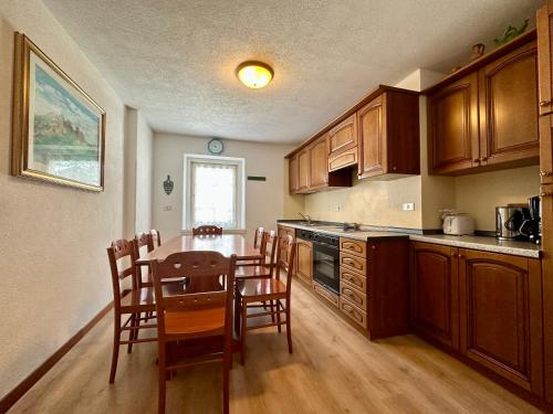 una cocina con armarios de madera, mesa y sillas en Central Apartment Canazei en Canazei