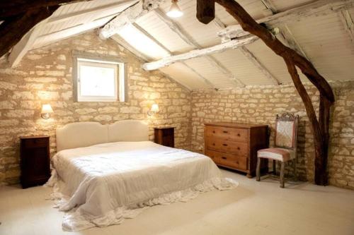 a bedroom with a white bed and a chair at Gîte La Bergerie - Piscine - Jacuzzi - Paisible - Montcuq en Quercy blanc in Montcuq