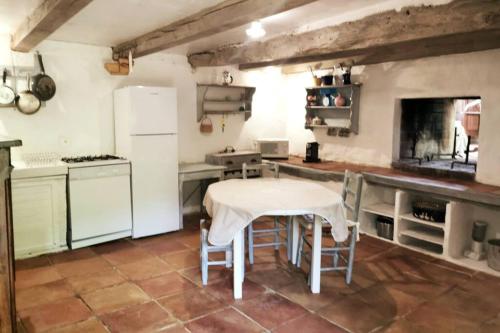 cocina con mesa y nevera blanca en Gîte La Bergerie - Piscine - Jacuzzi - Paisible - Montcuq en Quercy blanc en Montcuq