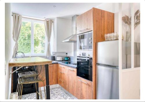 cocina con armarios de madera y nevera blanca en Studio calme dans un château au coeur de Caen en Caen