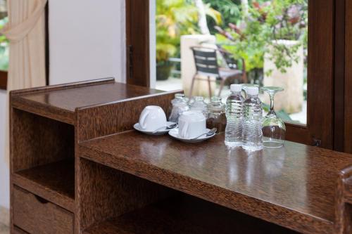 a wooden table with glasses and bottles on it at The Tunjung Ubud Retreat in Ubud