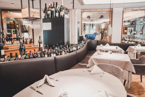 a restaurant with white tables and bottles of wine at Lodenwirt Residence in Vandoies