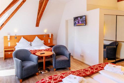 a hotel room with a bed and two chairs and a table at Bodensee-Hotel Kreuz in Uhldingen-Mühlhofen