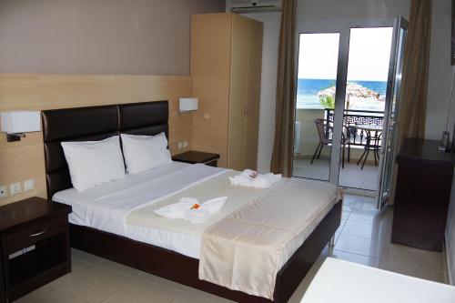 a bedroom with a bed and a balcony with the ocean at Rachoni Resort in Skala Rachoniou