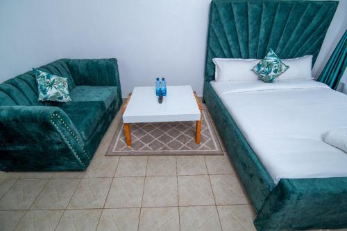 uma sala de estar com dois sofás verdes e uma mesa em The Green Apartment em Ruaka