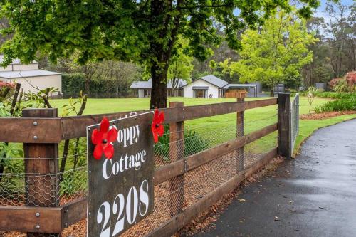 a wooden fence with a sign that reads our college at Unique and secluded Poppy Cottage in Bilpin