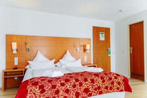a bedroom with a large bed with red and white sheets at Bodensee-Hotel Kreuz in Uhldingen-Mühlhofen