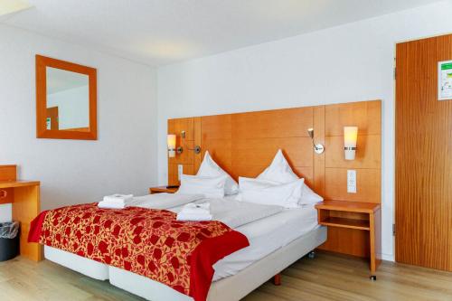 a hotel room with a large bed with a red blanket at Bodensee-Hotel Kreuz in Uhldingen-Mühlhofen