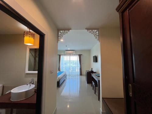 Krabi Front Bay Resort في مينْغكرابي: حمام مع مغسلة وسرير في الغرفة