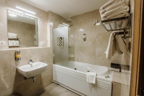 a bathroom with a sink and a tub and a shower at Hotel Nais in Niš