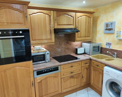a kitchen with wooden cabinets and a black appliance at GÎTE DE LA FONTAINE in Wangen