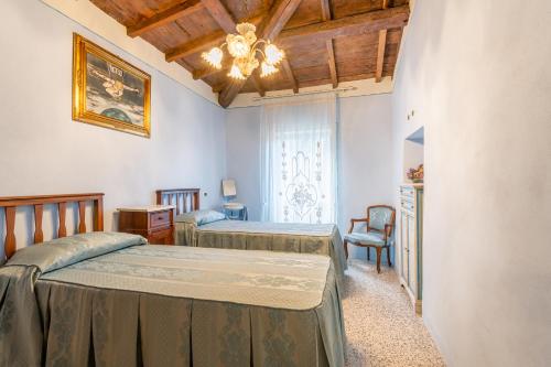 1 dormitorio con 2 camas y lámpara de araña en Grillo Rosso 8, en Molazzana