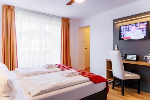 a hotel room with a bed and a desk and a television at Bodensee-Hotel Kreuz in Uhldingen-Mühlhofen
