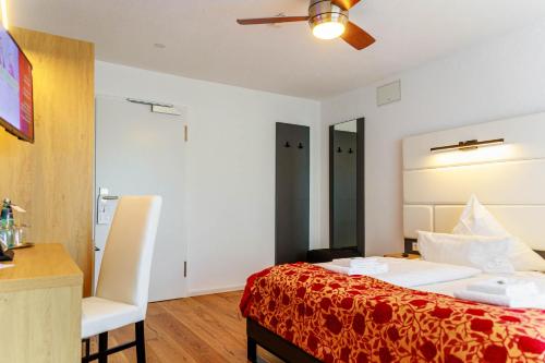 a bedroom with a bed and a desk and a chair at Bodensee-Hotel Kreuz in Uhldingen-Mühlhofen