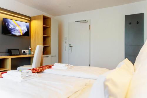 a room with a bed and a desk and a tv at Bodensee-Hotel Kreuz in Uhldingen-Mühlhofen