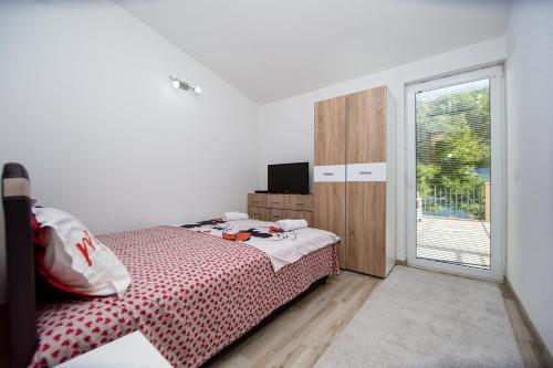 ein weißes Schlafzimmer mit einem Bett und einem Fenster in der Unterkunft Lana in Prčanj