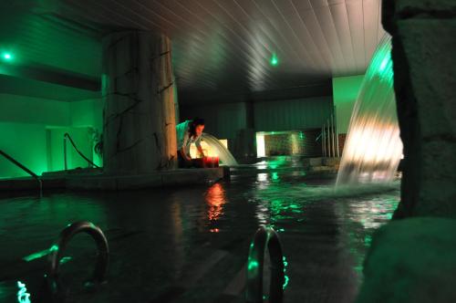 a person sitting next to a fountain in a pool at Gran Hotel Liber & Spa Playa Golf in Noja