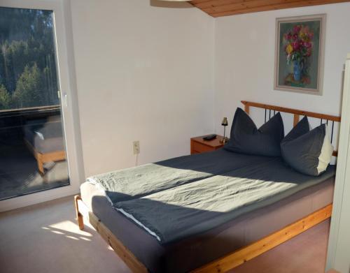 Un dormitorio con una cama con almohadas azules y una ventana en Kleine einfache Ferienwohnung in malerischer Umgebung Salzburgs, en Koppl