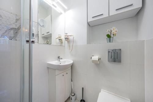 a white bathroom with a sink and a shower at Hello Apartments Modern Studio Sw Ducha in Gdańsk