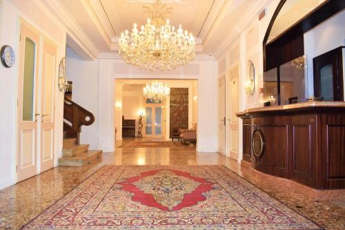 un ampio corridoio con lampadario a braccio e un grande tappeto di Hotel Edelweiss a Lido di Jesolo