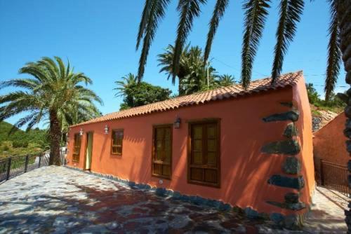 a small orange house with palm trees in the background at Casa Rural Las Avestruces in Agulo