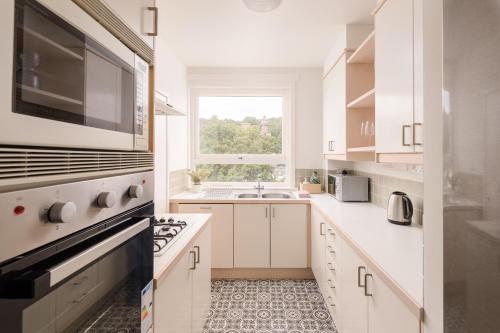 a white kitchen with a sink and a window at Calton Hill Lookout by Calton Living in Edinburgh