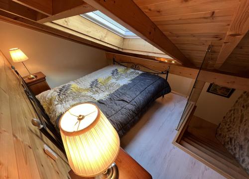 ein kleines Schlafzimmer im Dachgeschoss mit einem Bett und einer Lampe in der Unterkunft La Ferme aux Diligences in Neydens