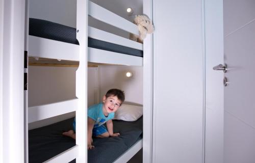 a little boy is sitting on a bunk bed at Résidence Coté Mer in La Grande-Motte