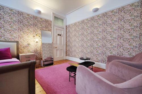 Luxury Artist Residence in Central London في لندن: غرفة معيشة مع أريكة وسجادة وردية