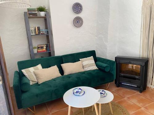 a living room with a green couch and a fireplace at Acogedora casa rural en Olvera ,La Morada in Olvera