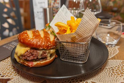 a black plate with a hamburger and french fries on a table at ibis La Bresse Gérardmer in La Bresse