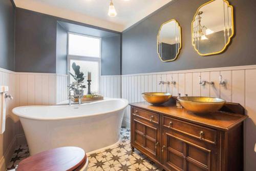 uma casa de banho com 2 lavatórios e uma banheira com espelhos em Pittman Cottage em Torquay