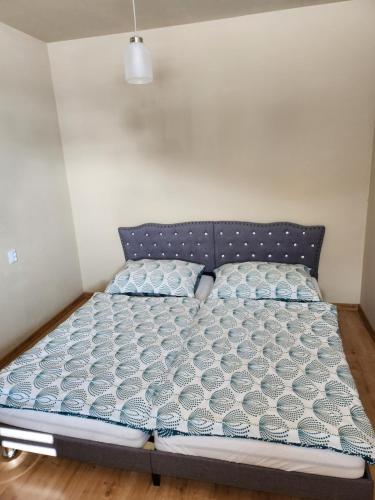 a bed in a room with a blue and white comforter at Apartmán Greenside in Michalovce