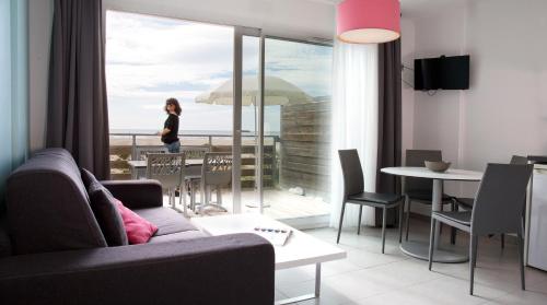 a living room with a couch and a table with an umbrella at Résidence Coté Mer in La Grande-Motte