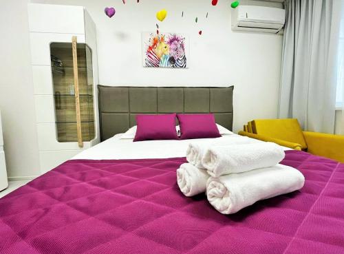 Un dormitorio con una gran cama púrpura con toallas. en Tevi Apartments, en Varna