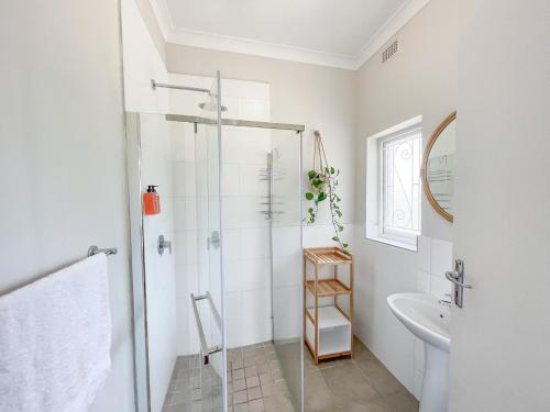a white bathroom with a shower and a sink at Leisure Isle Seaside Cottage in Knysna