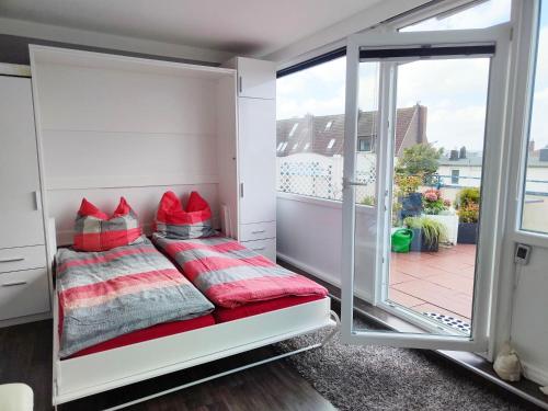 a bedroom with a bed with red pillows on a balcony at Ferienwohnung-Kassiopeia in Laboe