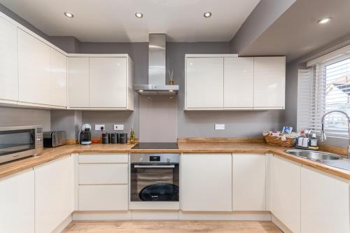 a kitchen with white cabinets and a sink at Castle Townhouse Kenilworth - Private Parking - 24 Hr Gym Access - Town Centre in Kenilworth