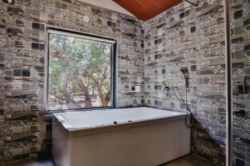 La salle de bains est pourvue d'une baignoire et d'une fenêtre. dans l'établissement Gir Lion Safari Camp by Trulyy, Sasan Gir, à Sodaori