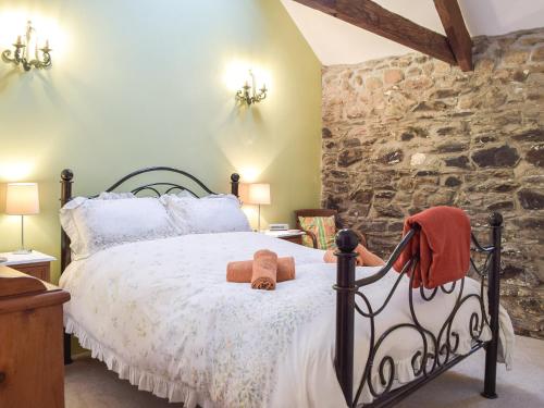 a bedroom with a bed and a stone wall at Swallow Lodge in Mathry