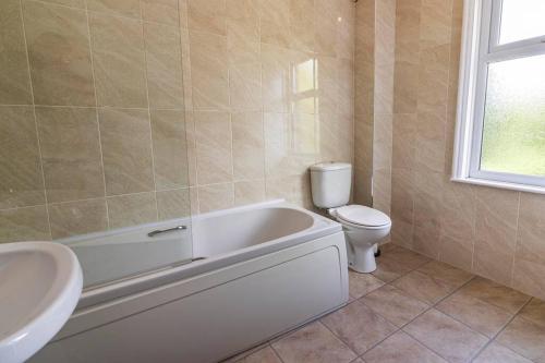 a bathroom with a tub and a toilet and a sink at 2 bed House sleeps 4 Long Eaton Nottingham Free parking Breedon in Long Eaton