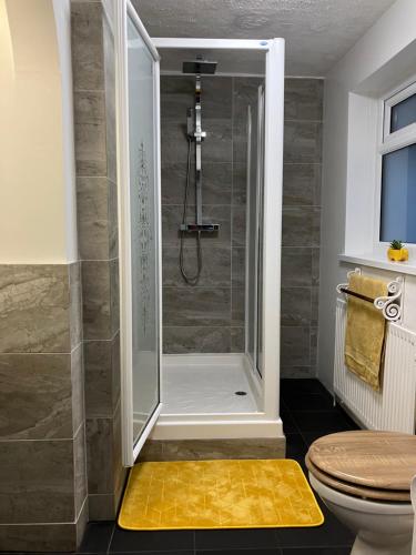 a bathroom with a shower with a yellow rug at Lovely family seafront property in Burnham-on-Sea in Burnham on Sea