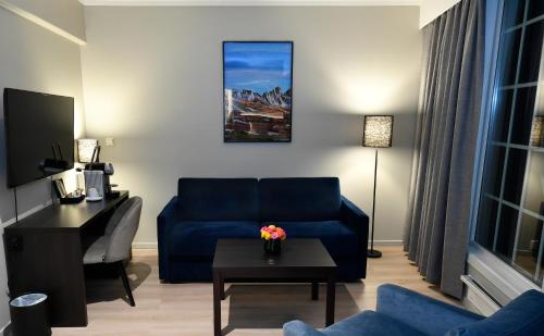a living room with a blue couch and a table at Thon Partner Hotel Baronen in Ålesund